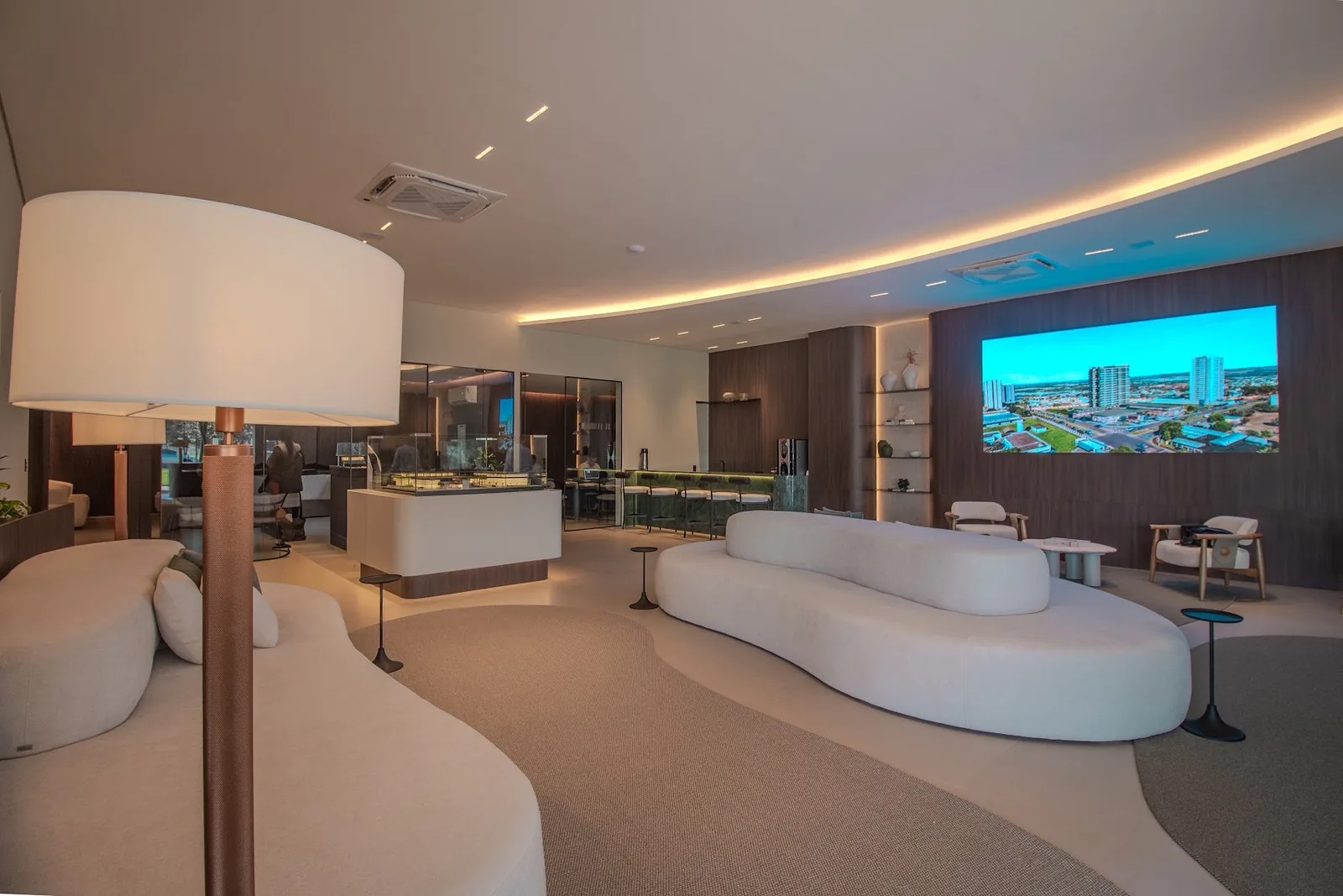 Lounge da central de vendas, com a maquete e o telão
